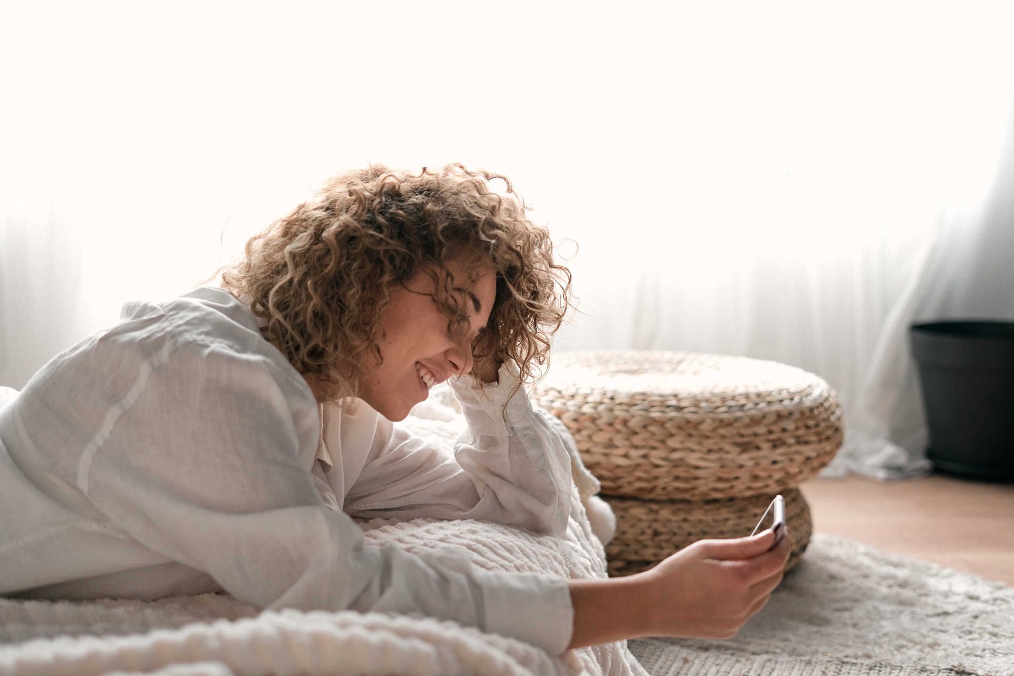 Content young woman touching head and using smartphone on bed