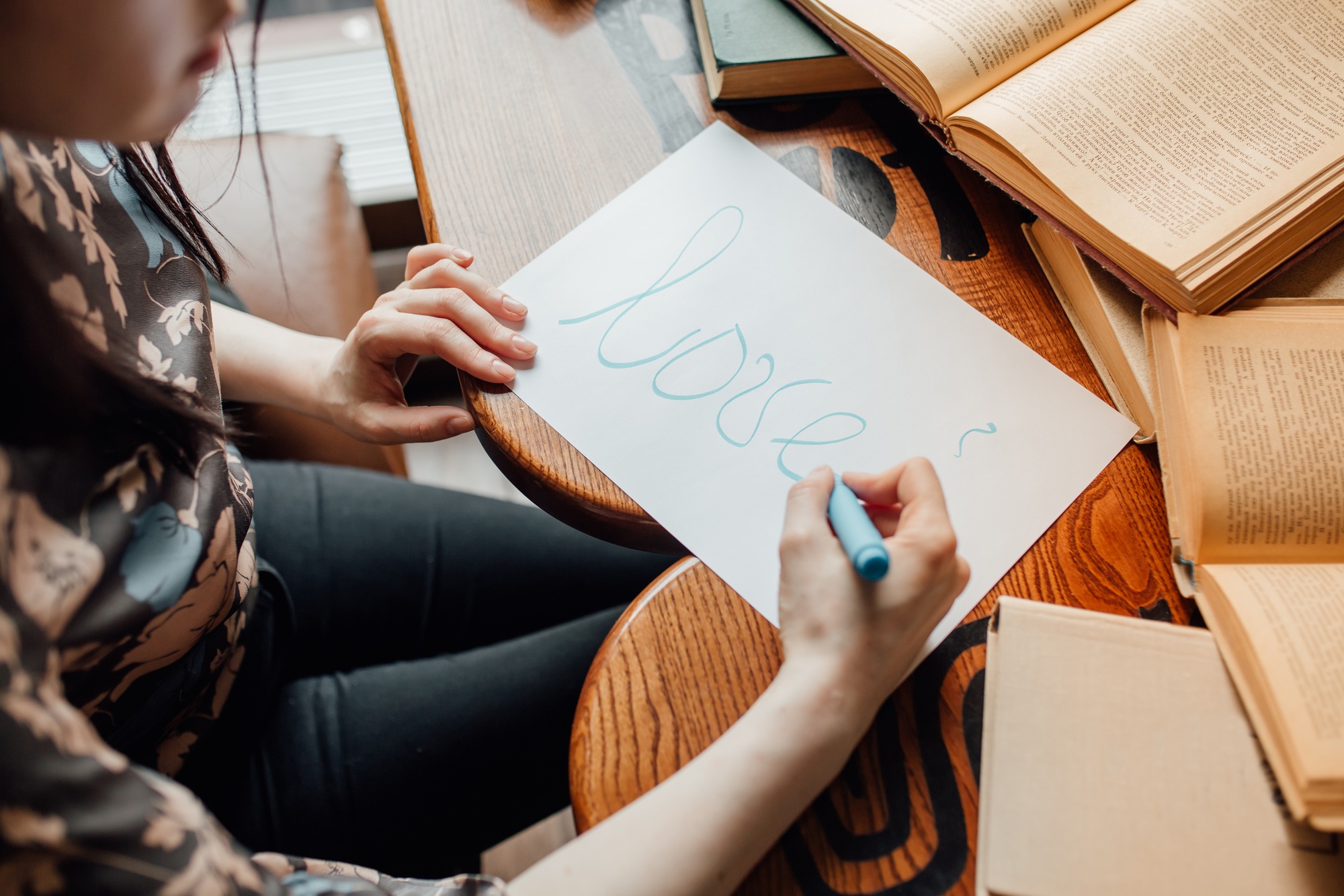 a girl writes on a sheet the word "Love"