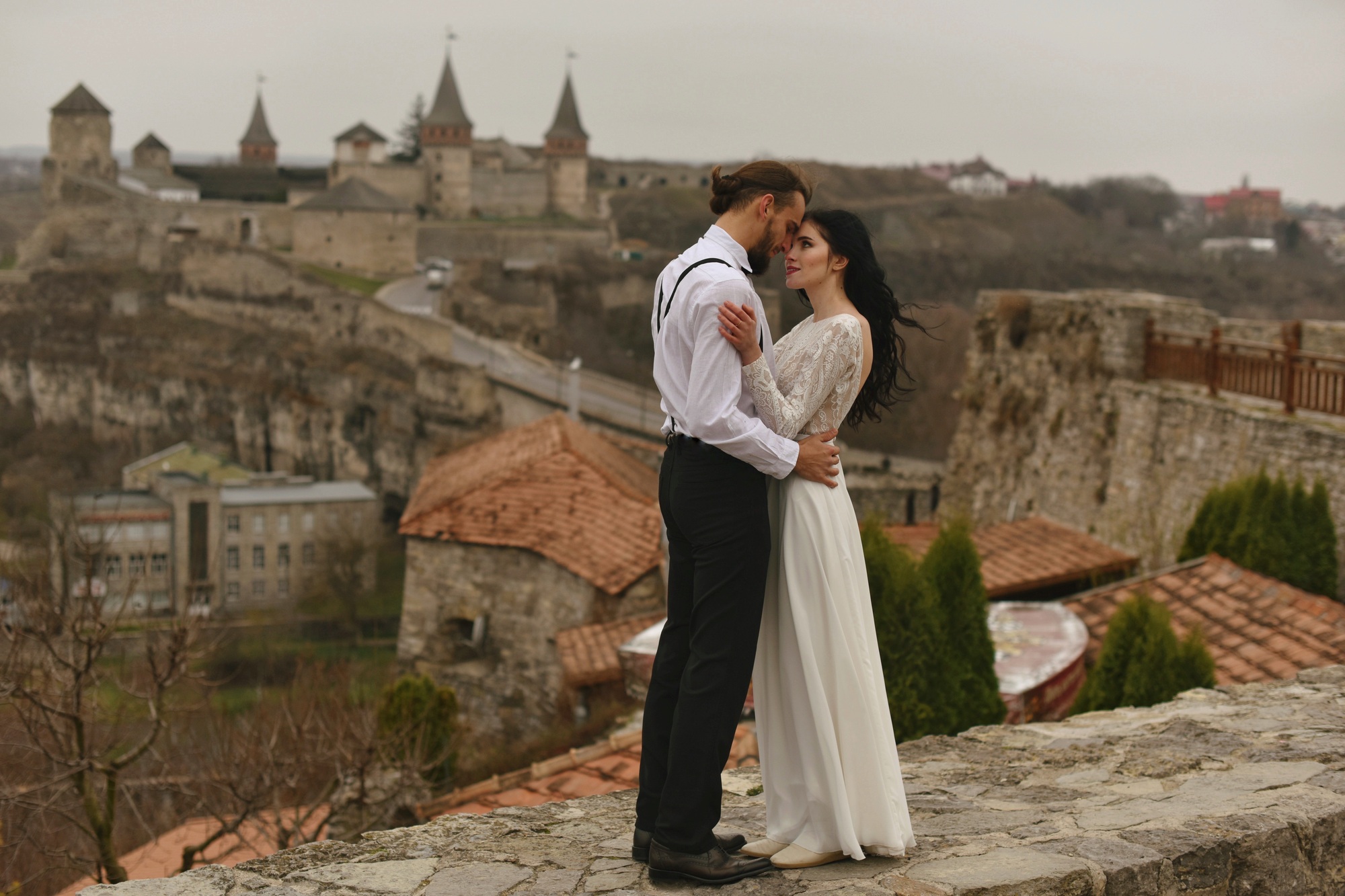 bride and groom in love look at each other and pronounce wedding vows on historic castle background