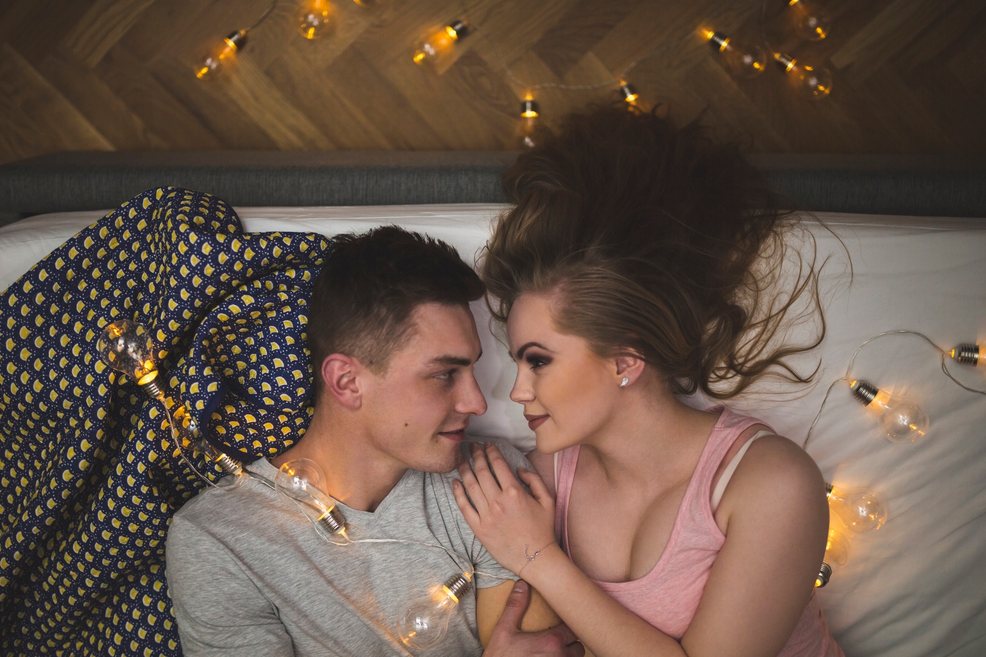 Romantic young couple cuddling in bed with fairy lights