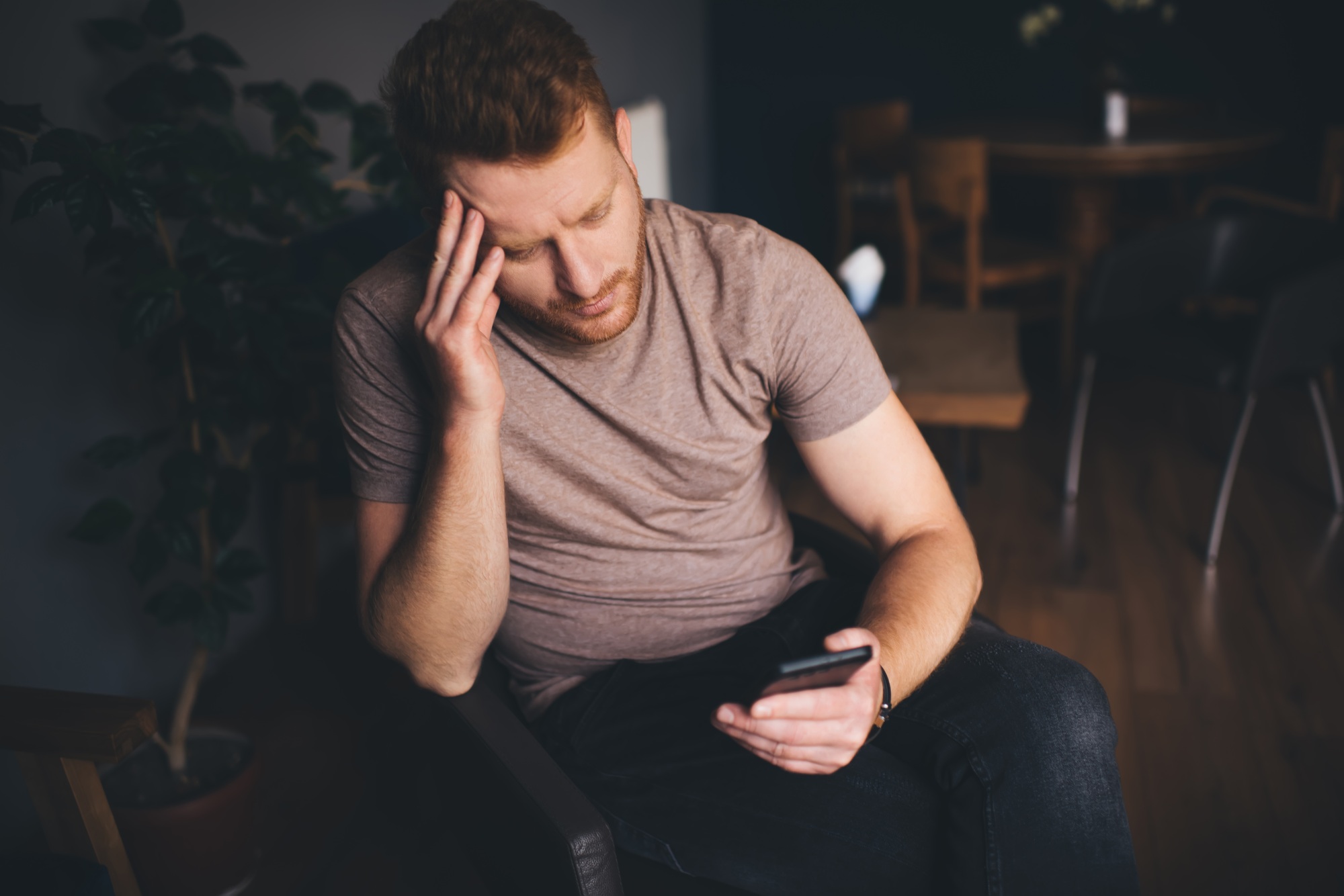 unhappy bearded man with modern smartphone reading bad news while browsing website page