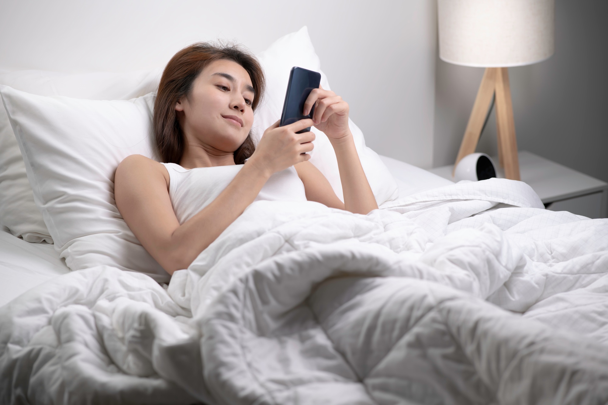 Woman using phone on bed