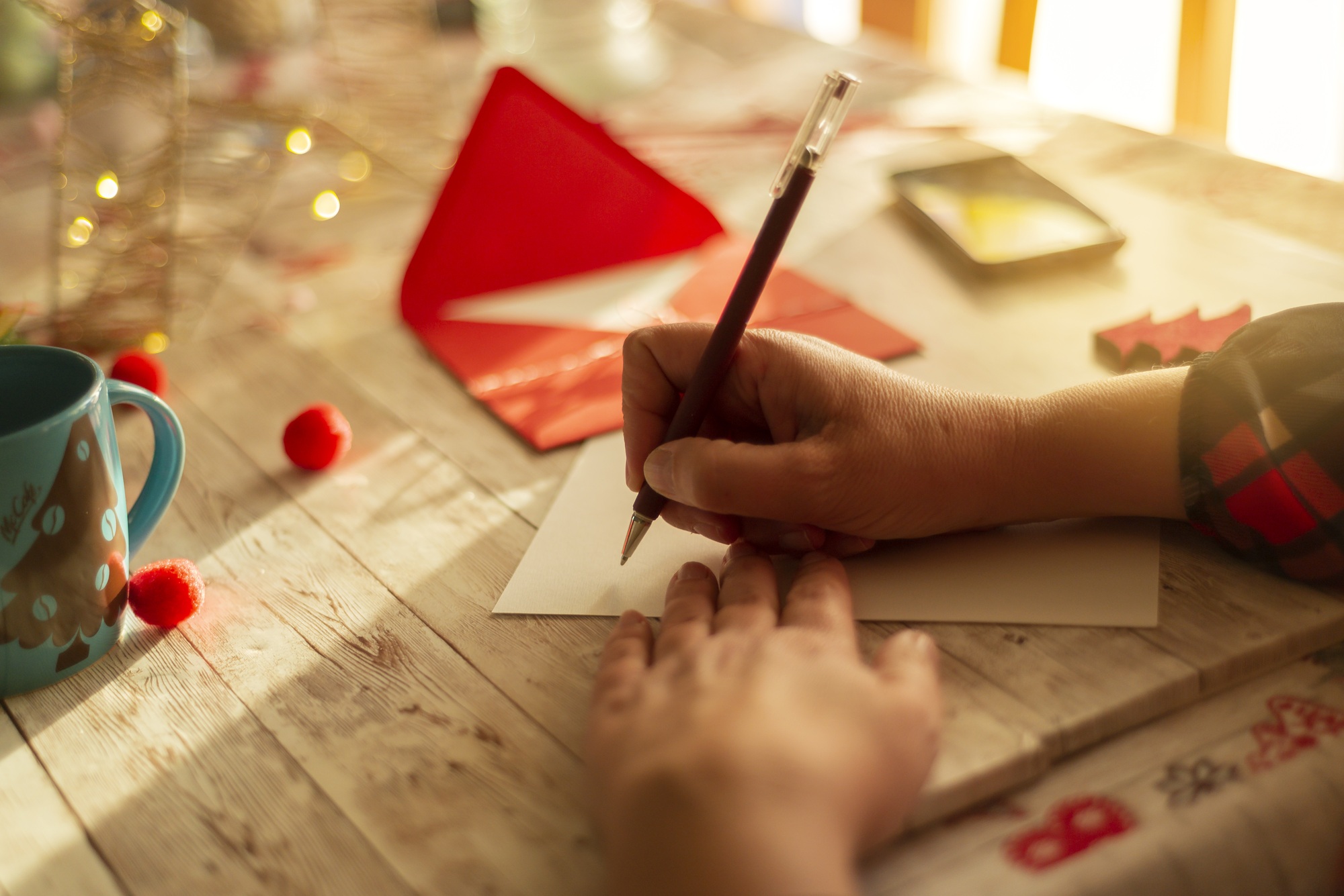Person writing Christmas letter greeting card holiday wishes.
