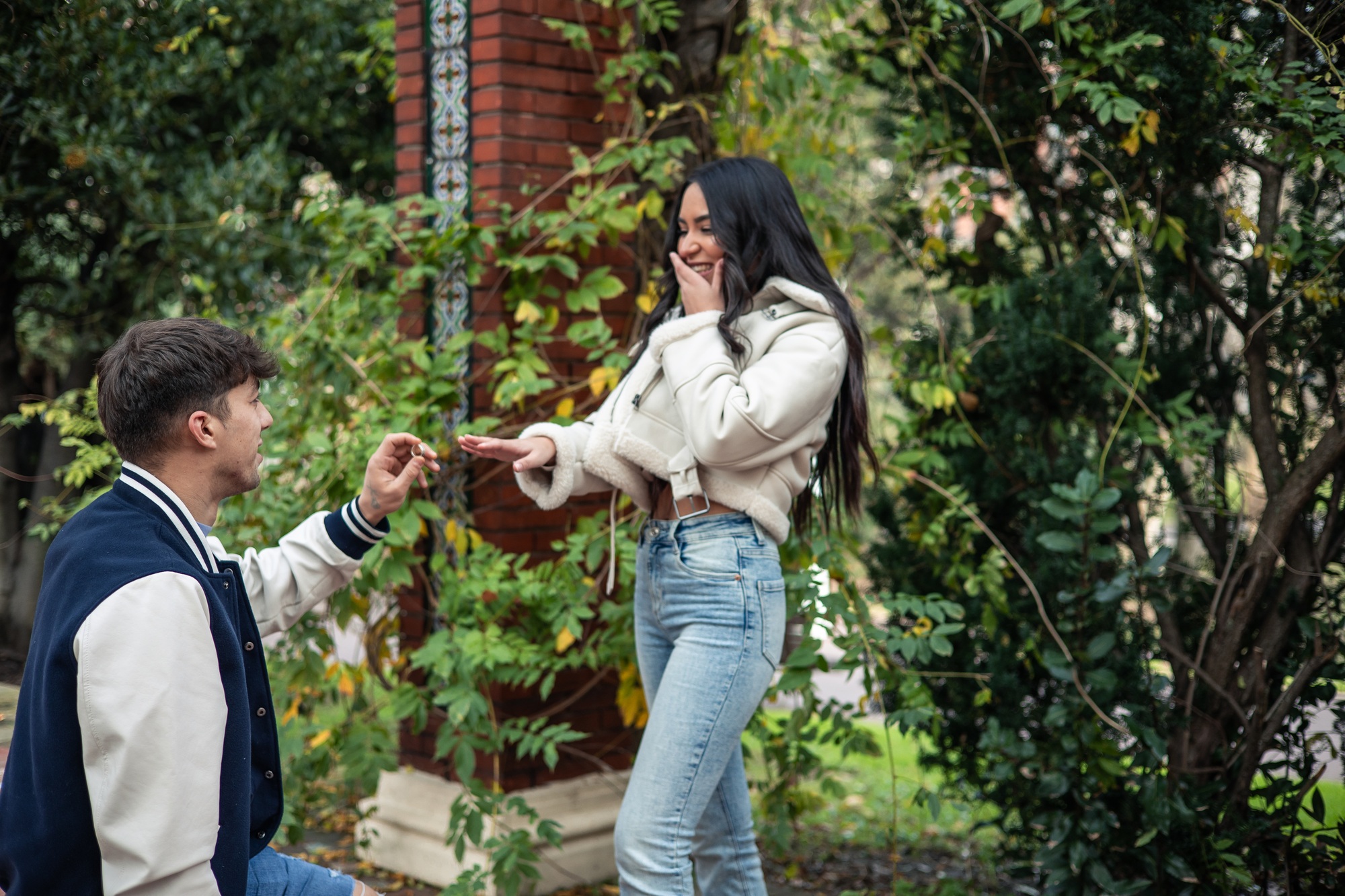 young man kneeling asking his latina girlfriend to marry him